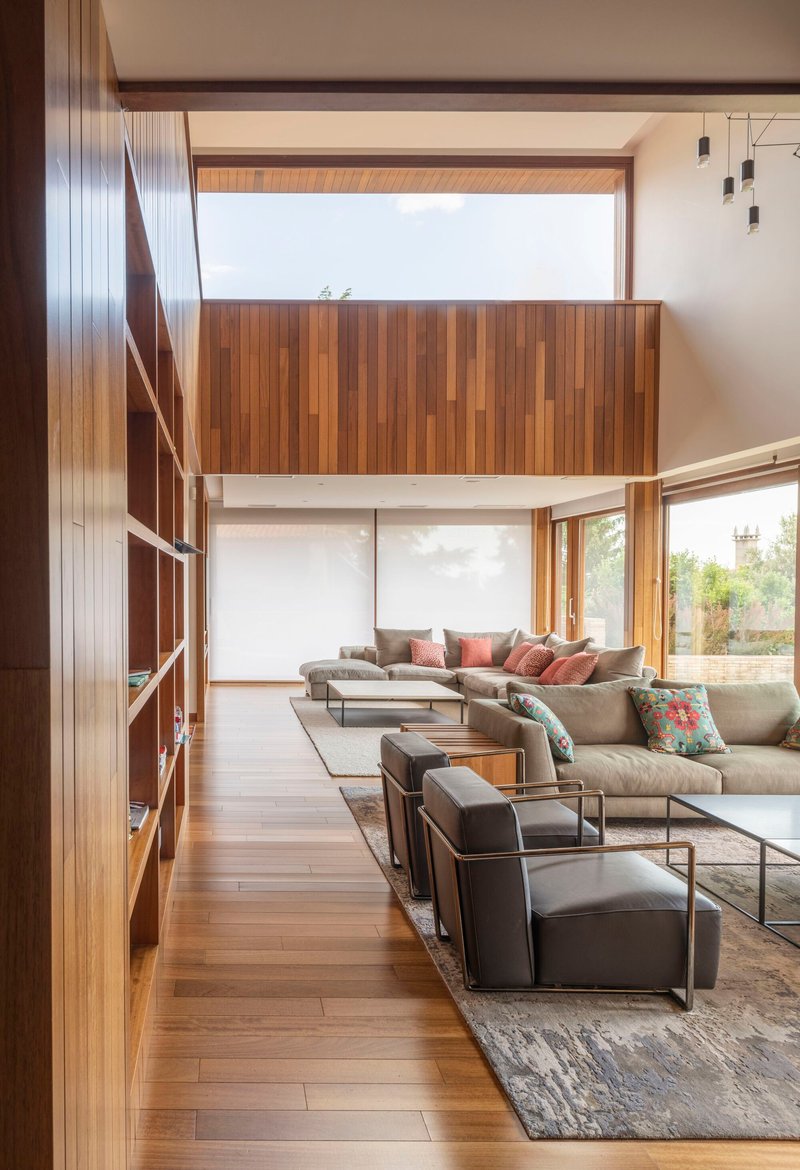 Living room with mezzanine bridge and built-in timber shelving along one wall