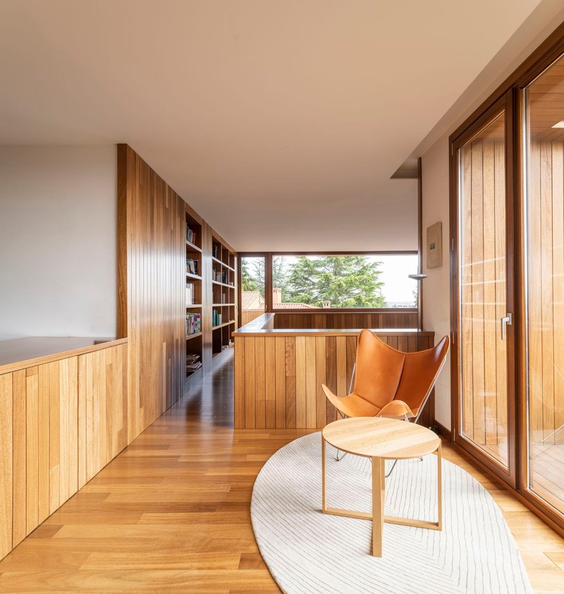 Hallway seating area with timber slat walls and bookshelf overlooking a courtyard