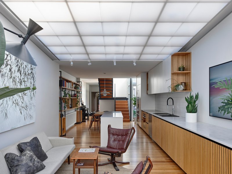 Open living space with translucent ceiling panels and timber kitchen joinery under track lighting