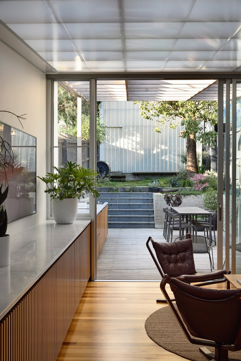 Living area opening through sliding glass doors to courtyard with stepped concrete planters and tree