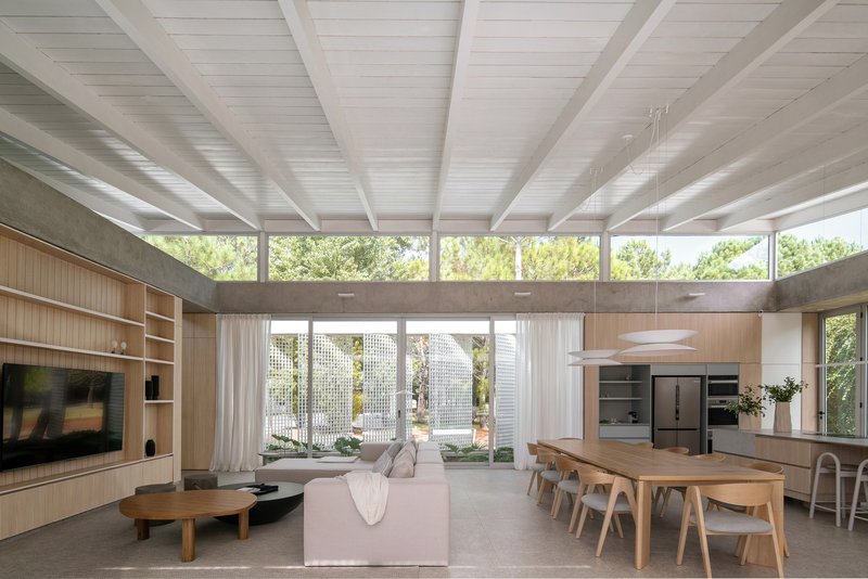 Open-plan living and dining area with exposed timber beams and clerestory windows overlooking an interior courtyard