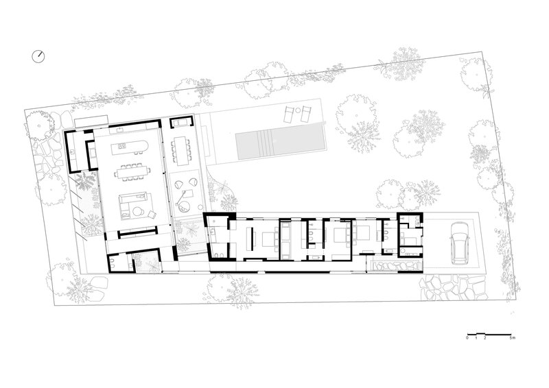 Floor plan drawing showing an L-shaped residence with interior rooms and surrounding landscape