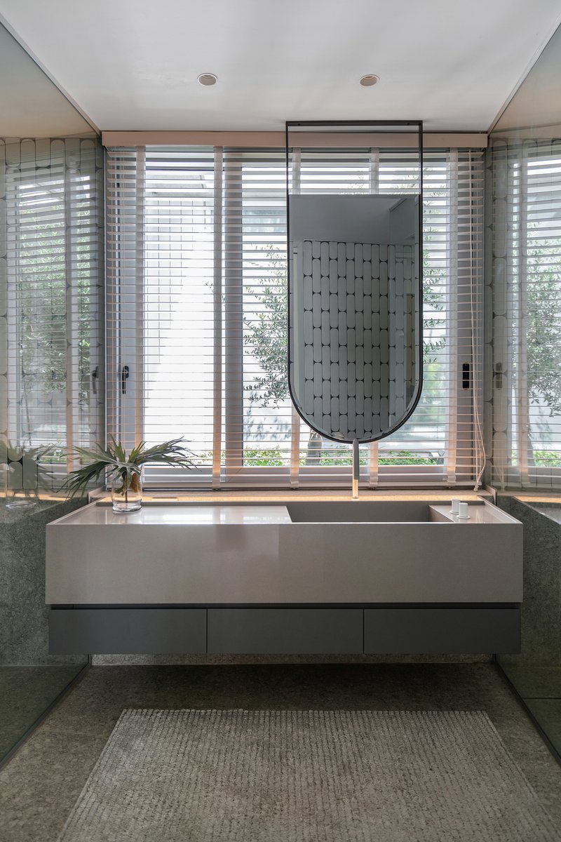 Floating vanity with rectangular basin below horizontal shuttered windows overlooking greenery outside