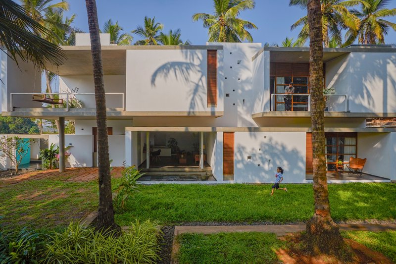 Garden facade with white rendered walls and timber shutters casting palm shadows in afternoon light