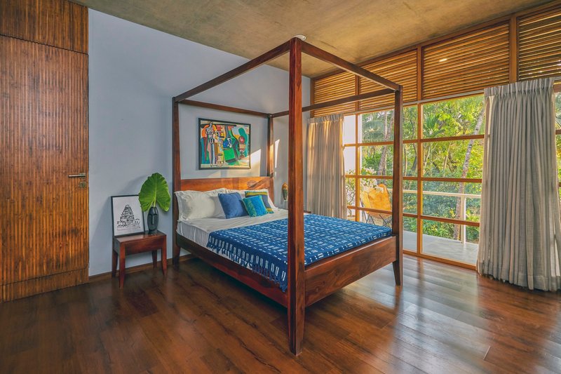 Bedroom with four-poster timber bed and grid-paned sliding doors opening to a private balcony