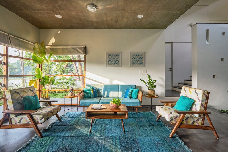 Living room with exposed concrete ceiling and gridded windows overlooking greenery in morning light