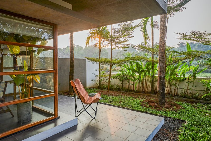 Private terrace with leather chair opening to planted garden through timber-framed glass doors at dawn