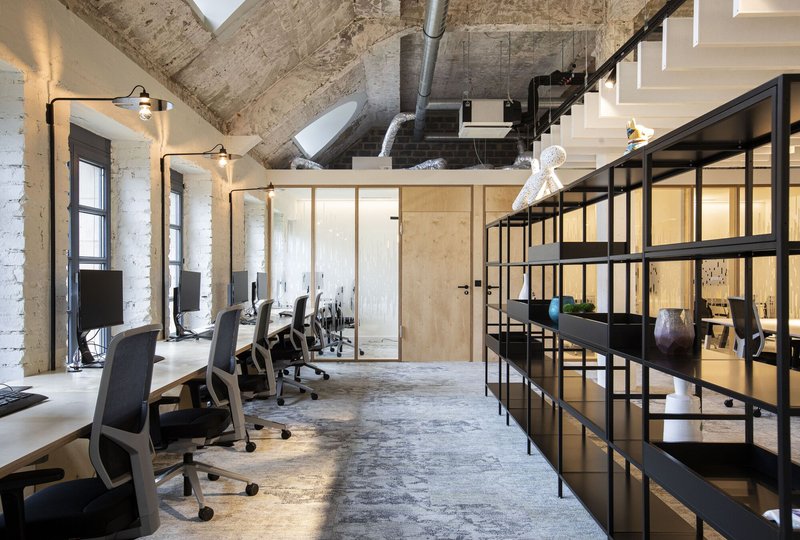 Workstation area with black steel shelving units alongside painted white brick walls and exposed ductwork