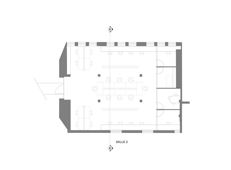 Floor plan drawing depicting a rectangular workspace with central desking area and corner amenities