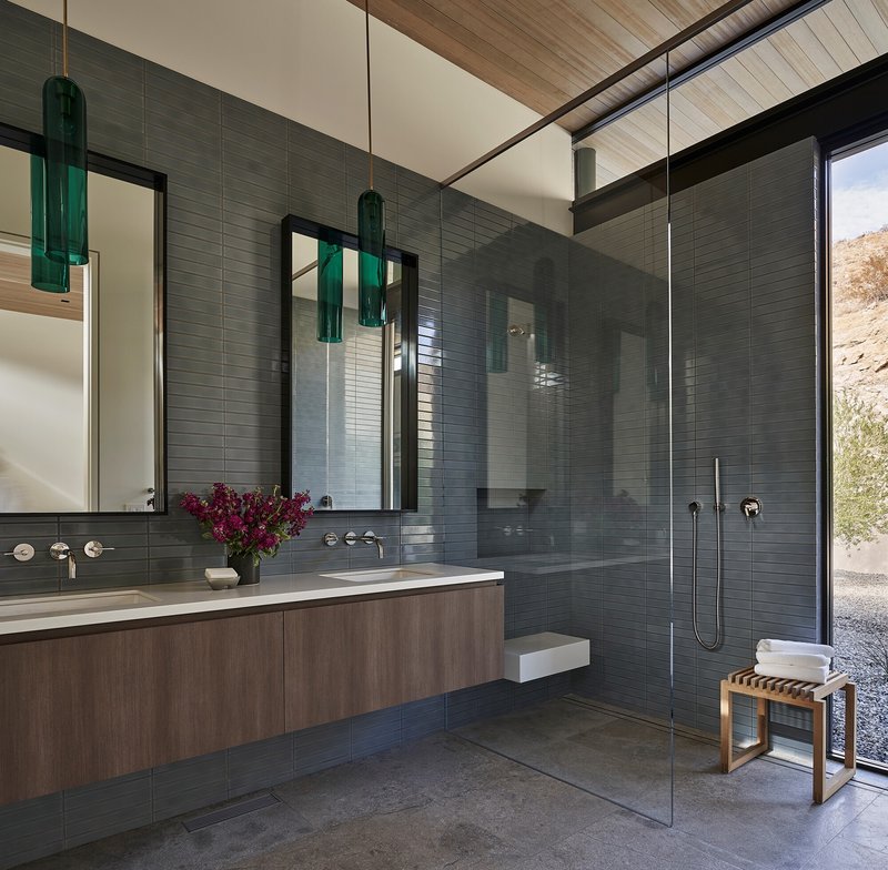 Bathroom with grey tile wall, floating vanity, and glass-enclosed shower stall