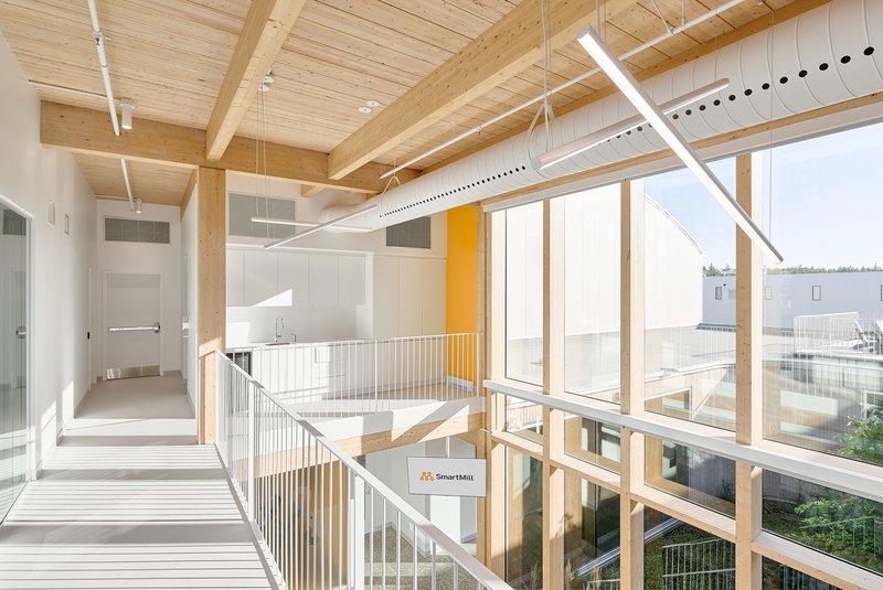 Upper corridor with exposed timber beams and glazed railing overlooking a central atrium