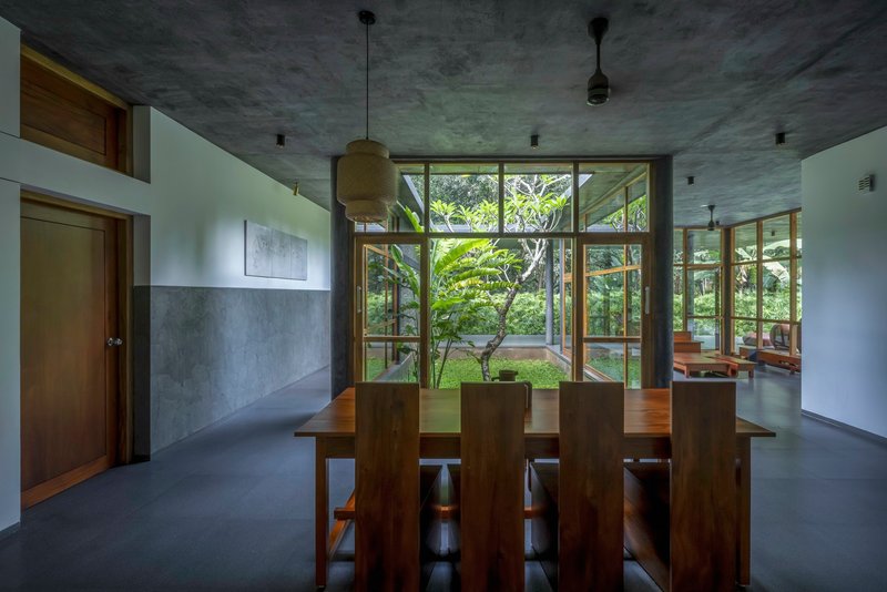 Dining area with timber table and chairs beneath board-formed concrete ceiling and pendant light fixtures