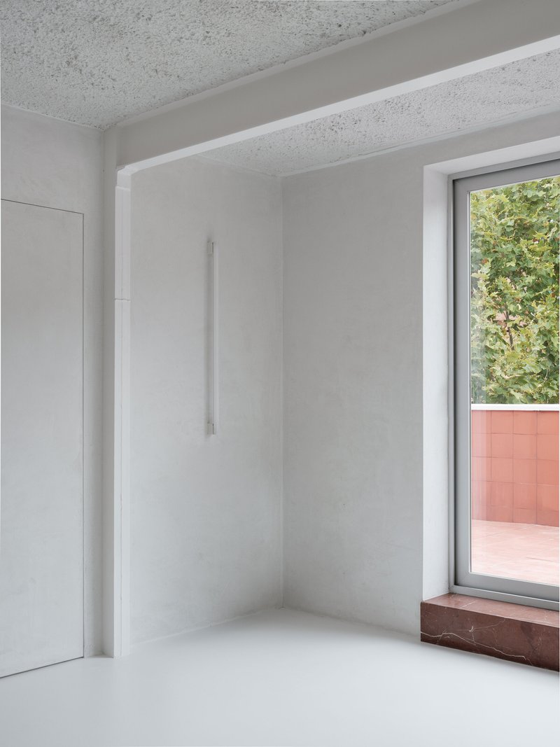 Interior corner with window opening to planted balcony and red marble sill beneath terrazzo ceiling