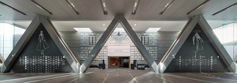 Symmetrical view down a corridor with triangular steel portals framing a polished stone floor