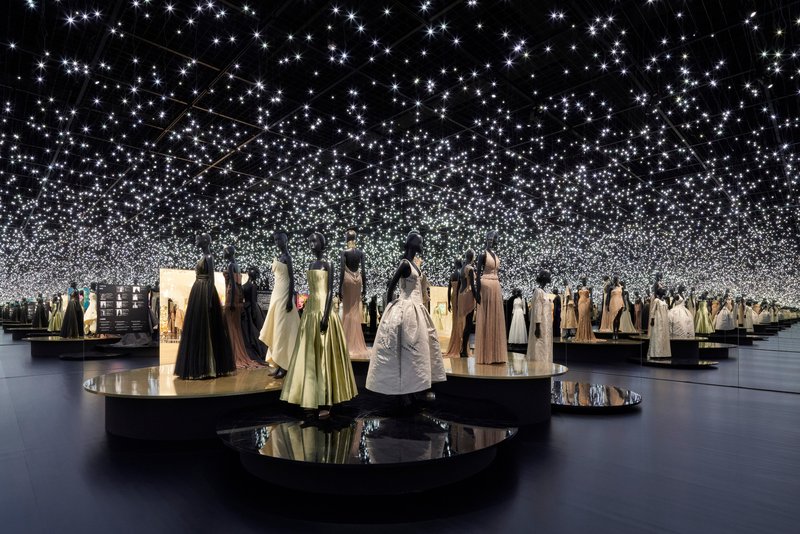 Exhibition gallery with circular display plinths and a field of suspended starlight points overhead