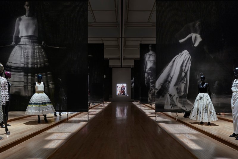 Gallery hall with timber flooring and large-scale black and white photographic projections flanking display cases