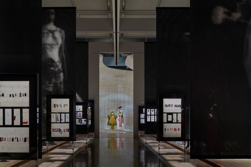 Axial view through exhibition hall with framed display cases flanking a central corridor