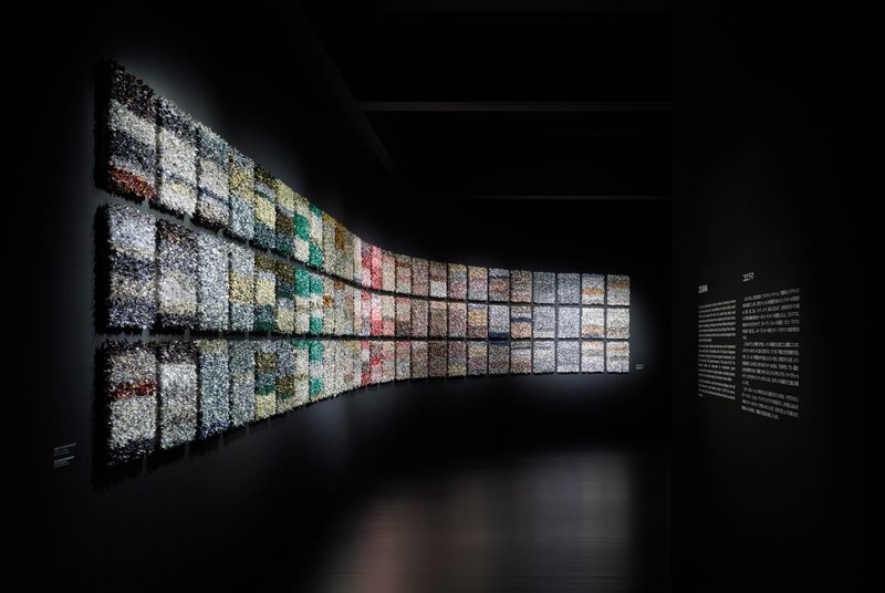 Curved backlit wall composed of gridded image panels transitioning through the color spectrum