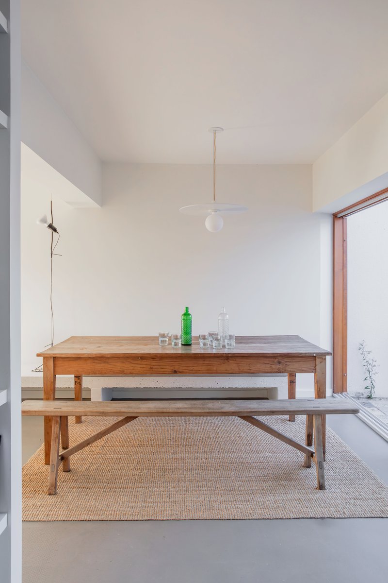 Dining area with timber table and benches beneath a pendant light beside a courtyard window
