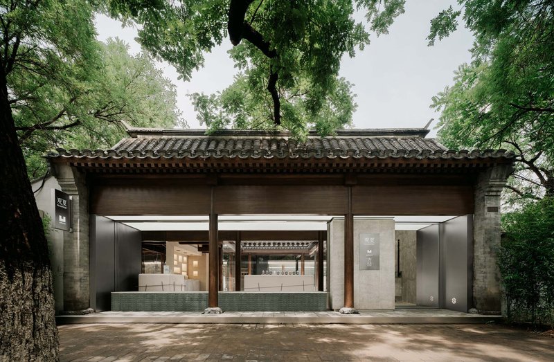 Frontal view of the open pavilion structure showing timber beams beneath curved tile eaves without pedestrians