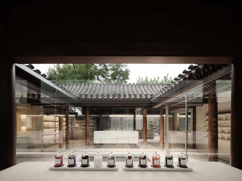 View through a display window toward the interior courtyard with timber columns and row of vessels on the sill