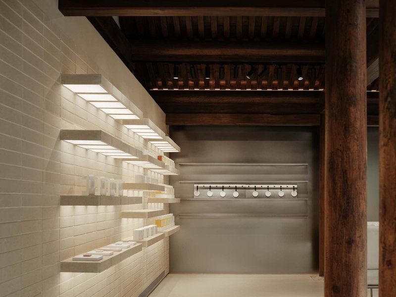 Illuminated product shelves wrapping around timber columns in a retail space with slatted ceiling above