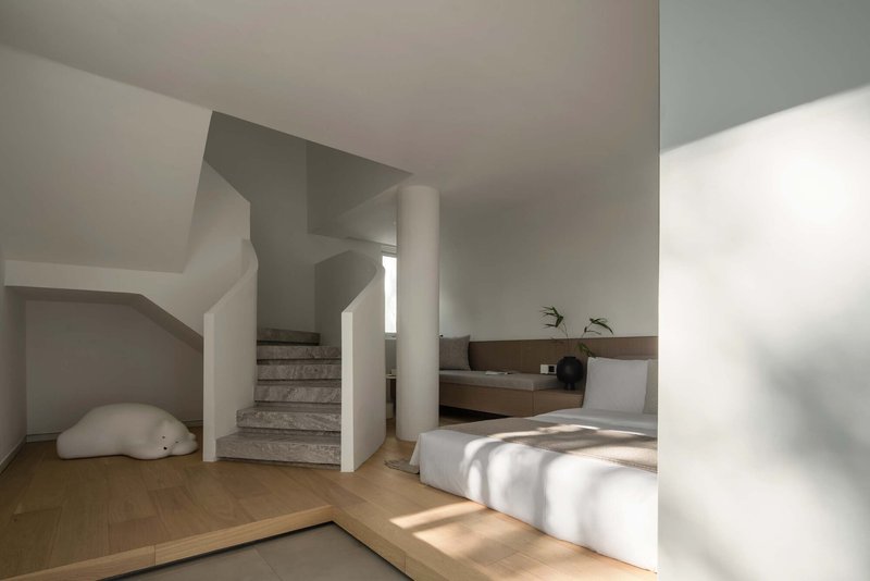 Concrete stair with curved white walls and wood flooring in bright natural light