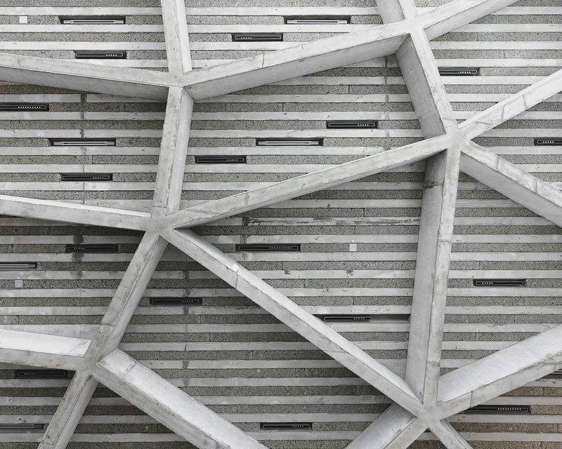 Upward view of textured ceiling with diagonal timber beams and integrated linear lighting