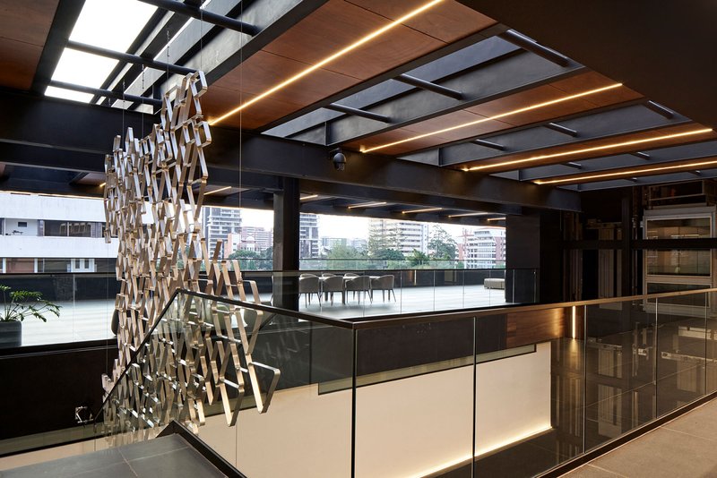 Kitchen island with backlit base below exposed ceiling beams with integrated linear lighting