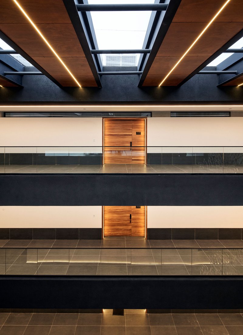 Symmetrical view of timber doors and glass balustrades across four levels beneath a skylit ceiling