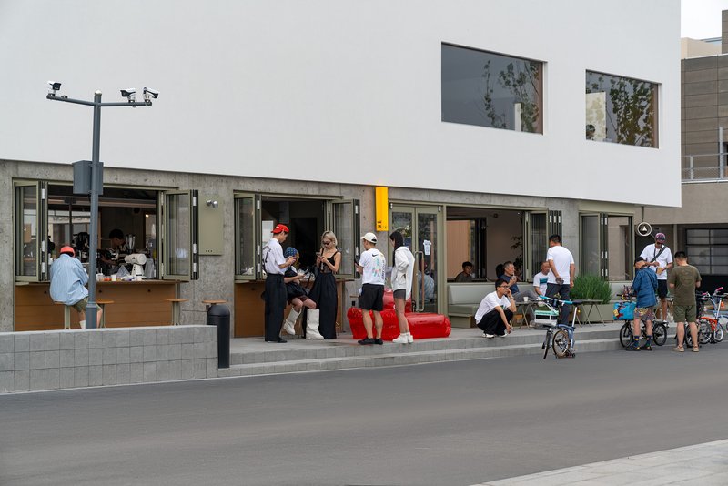 Folding storefront windows opening onto plaza where crowds gather on a sunny afternoon