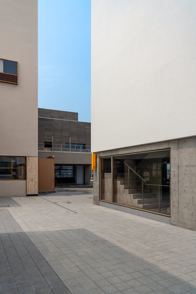 Paved courtyard showing concrete stair entry with glass door and timber cladding at dusk