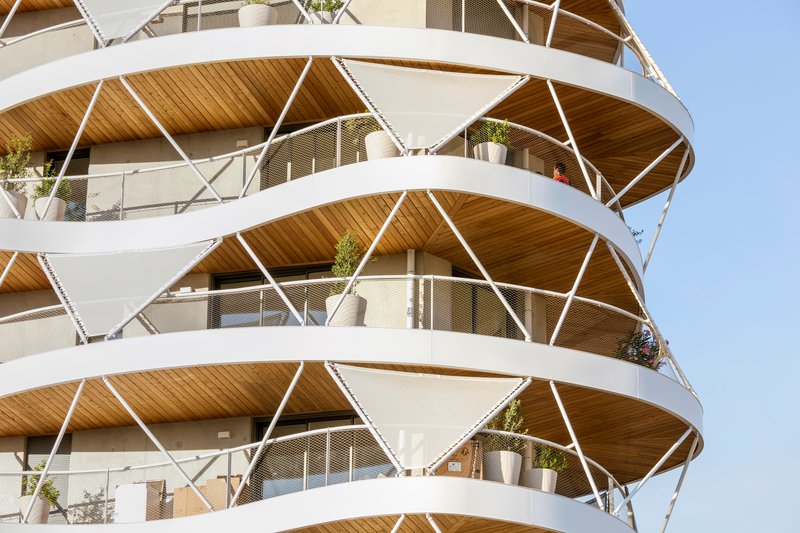 Close-up of the helical balcony structure with timber soffits and white steel bracing carrying potted plants
