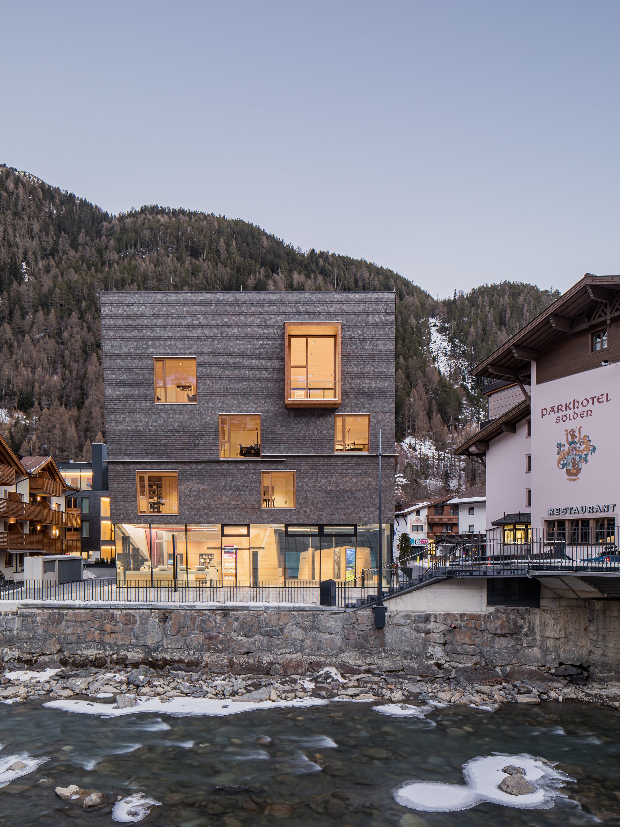 Obermoser + Partner Architekten Wrap an Alpine Tourist Center in Pre-Greyed Larch Shingles