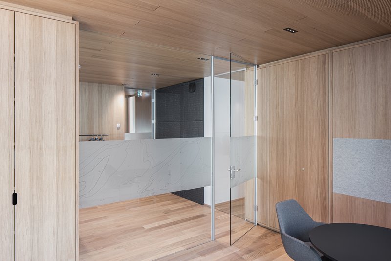 Glass-partitioned meeting room with white marble half-height walls and timber paneling throughout