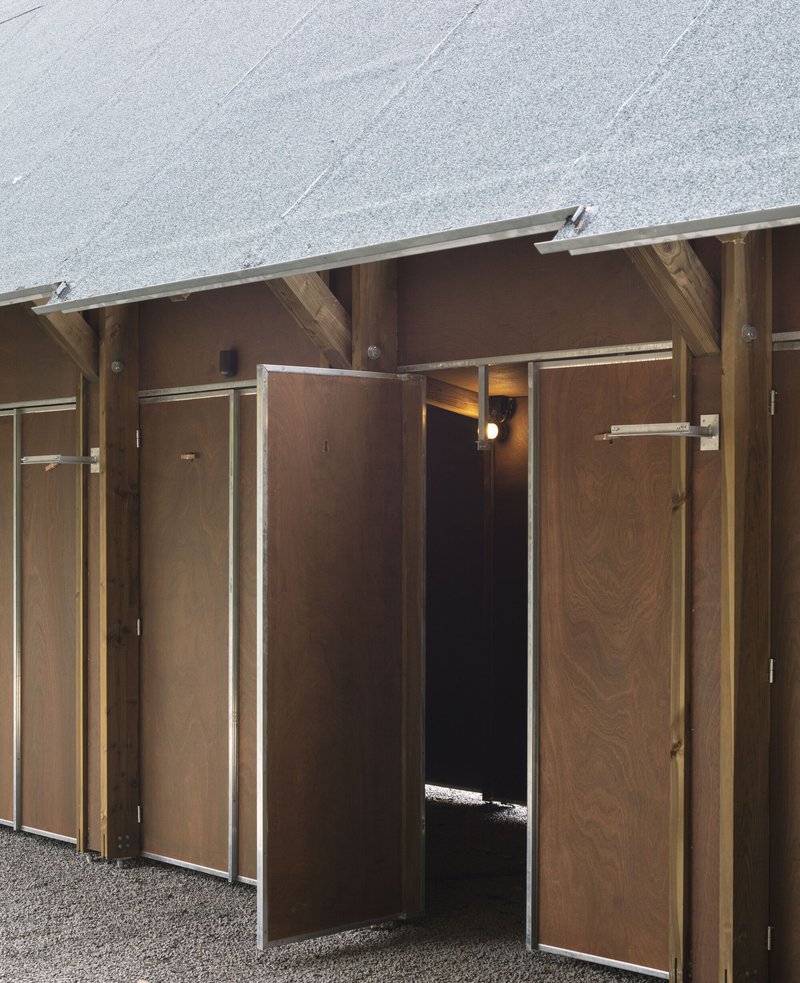 Close-up of timber-framed doorways with plywood panels and metal edging beneath a pitched gravel roof