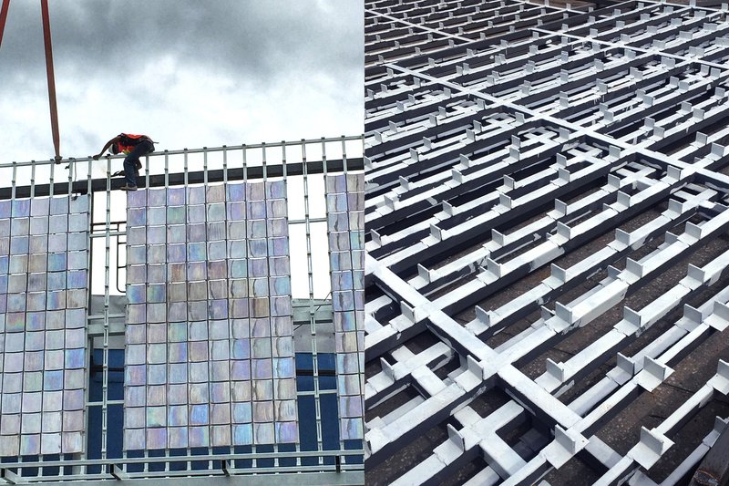 Worker installing iridescent tile panels on the gridded metal framework under cloudy skies