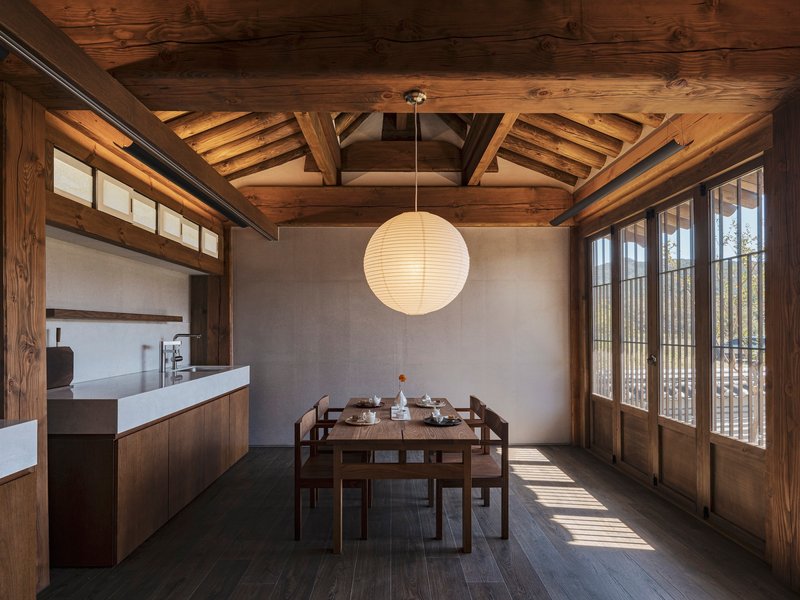 Dining area with exposed timber ceiling beams and paper lantern illuminated by afternoon sunlight