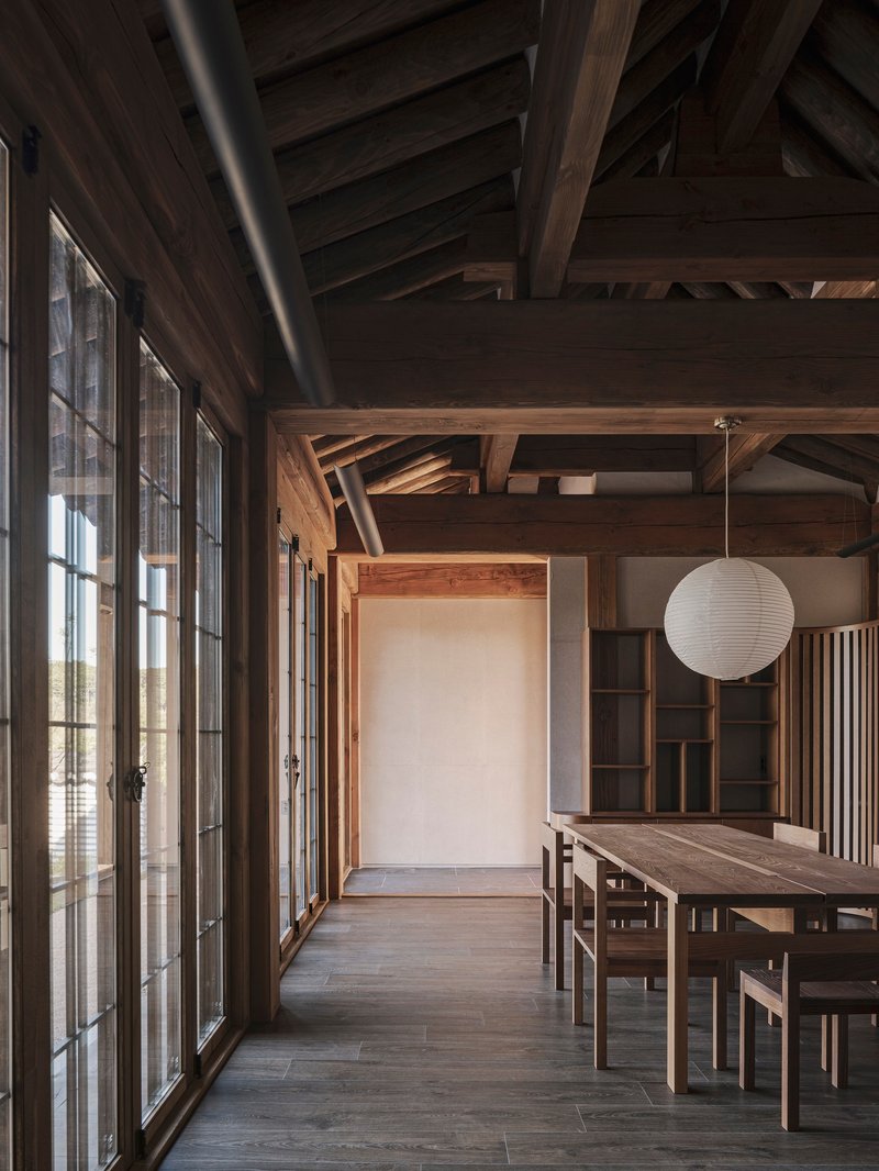 Dining area with exposed timber framing and a paper globe pendant above the table