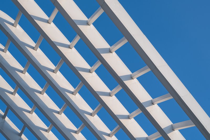Repeating white horizontal louvers casting sharp shadows against a deep blue sky