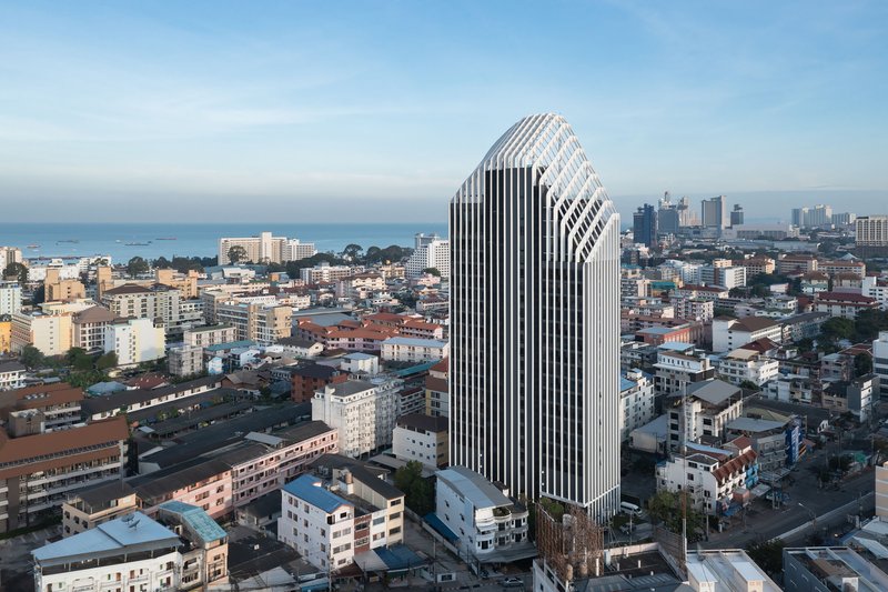 Aerial view of the white vertical fin facade rising above the surrounding residential neighborhood at dusk