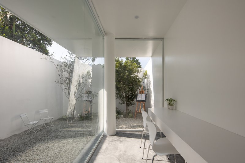 Interior view through glass walls toward twin gravel courtyards with planted trees