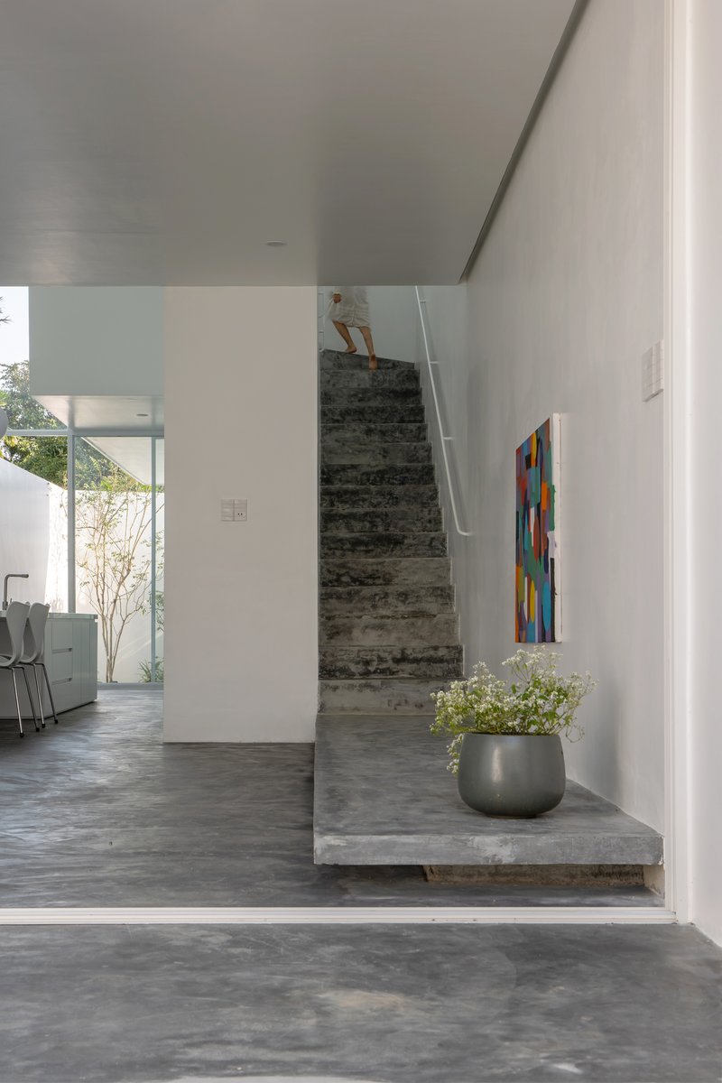 Board-formed concrete staircase rising from the living area with a figure ascending