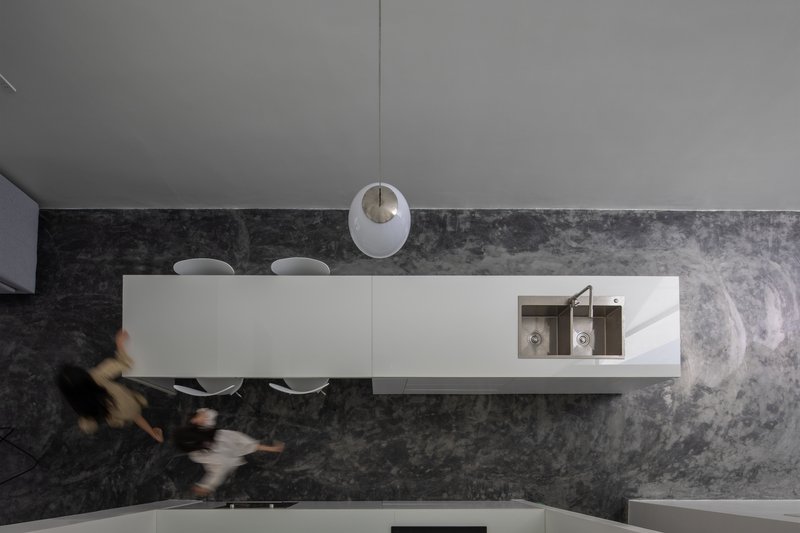 Overhead view of kitchen island with polished stone countertop and two figures passing