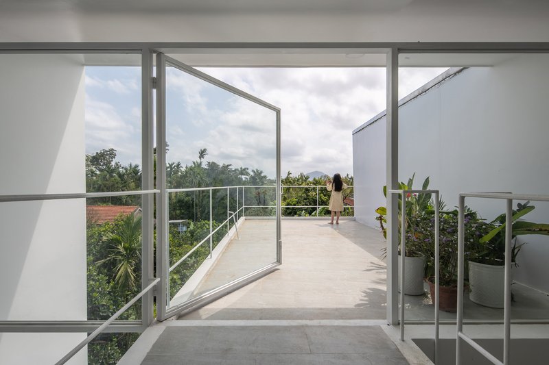 Roof terrace with steel frame doors opening to view of distant mountains and vegetation