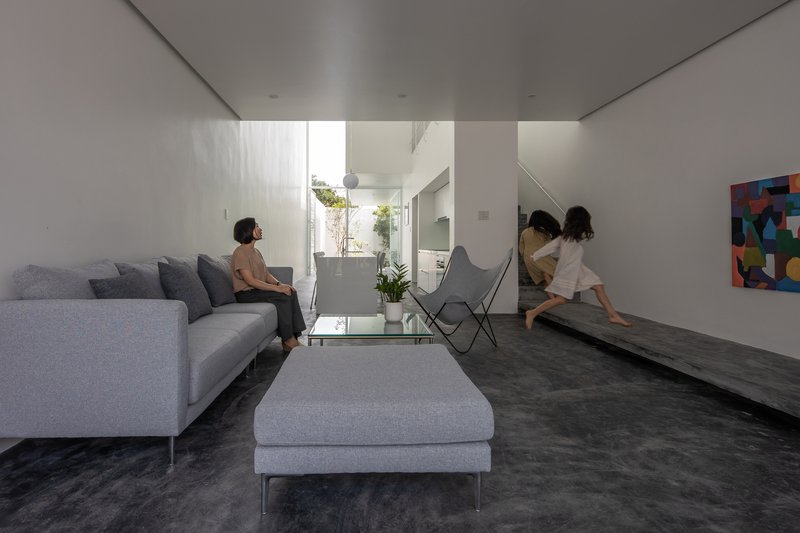 Living room with residents seated on grey furniture beneath diffused light from a courtyard skylight