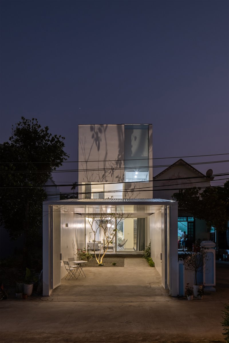 Street view of the translucent glass facade and open ground floor at twilight