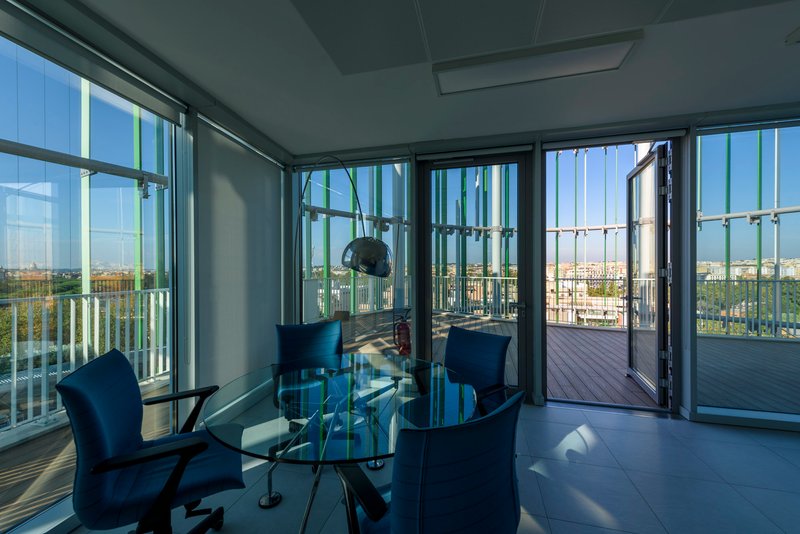 Interior dining space with floor-to-ceiling glazing opening to terrace beyond vertical screening elements
