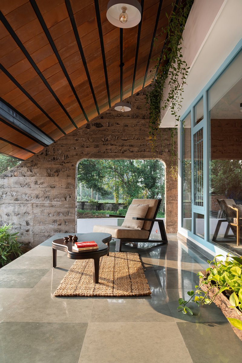 Covered terrace with boardformed concrete walls and arched opening framing garden beyond