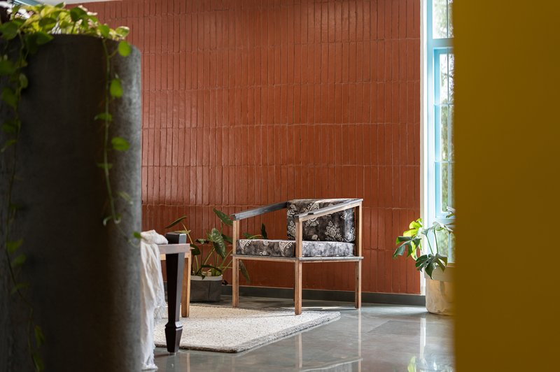 Seating area against terracotta tile wall with potted plants and blue window frame at edge